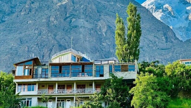 A two-story building with balconies, set against a mountainous backdrop.