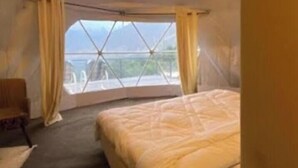 A bedroom with a bed, a chair, and a window with curtains.