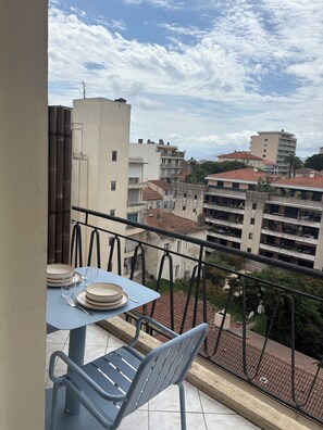 A balcony with a table set for dining, metal chairs, and a view of surrounding buildings. - Studio terrace Cannes, 10min train station, 15min beaches (Cannes)