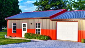 En byggnad med en röd och grå fasad, en vit garageport och en grusuppfart.