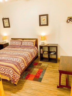 Um quarto com uma cama, mesas de cabeceira, um aparador, uma estante e uma pequena mesa.