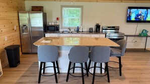 Een keuken met een granieten eiland, barstoelen, roestvrijstalen apparatuur en een televisie aan de muur.