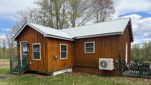 Een houten chalet met een metalen dak, een trap en een airconditioning.