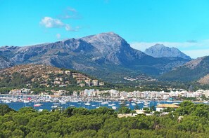 A coastal town with a marina, buildings, and mountains in the background. - Stylish Retreat, A/C, Private Pool - Walking Distance (15mins) to Port de Pollenca & Beach! (Pollença)