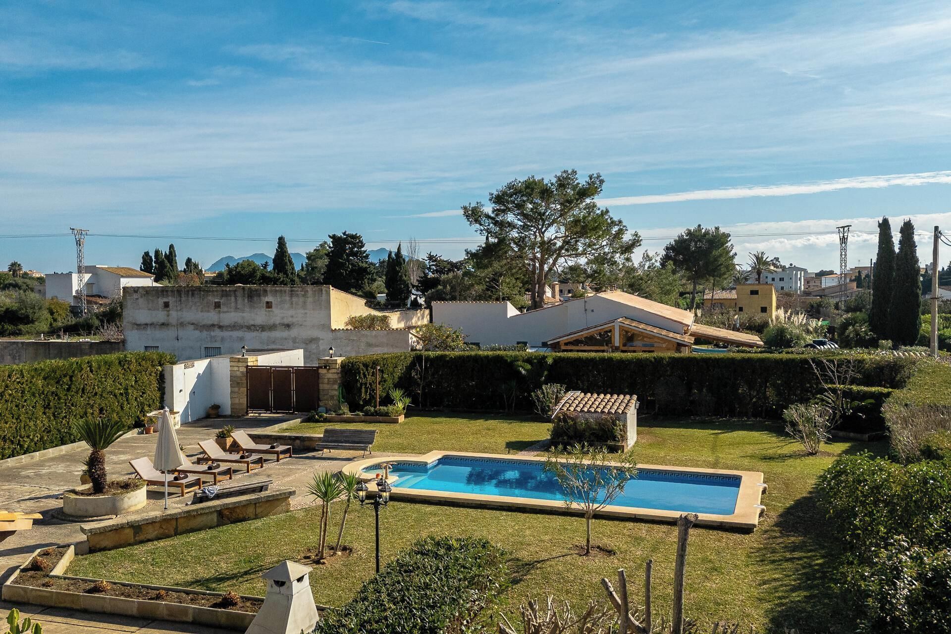 A residential property with a swimming pool, lounge chairs, and a well-maintained garden.