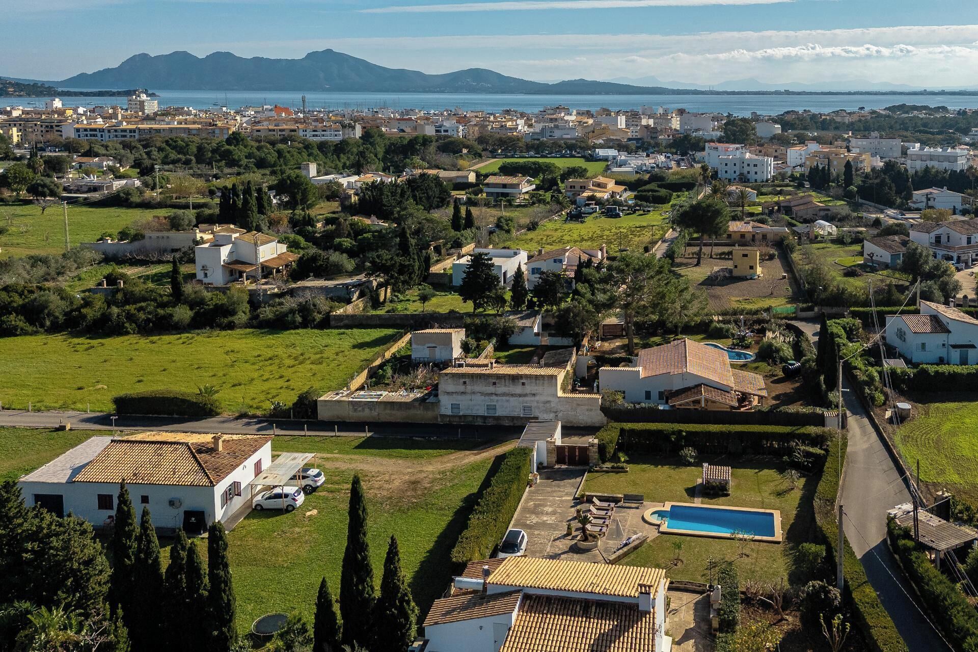 An aerial view of a residential area with houses, a swimming pool, and a road.