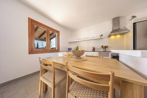 Una cocina moderna con una mesa de madera, sillas y un ventanal grande.