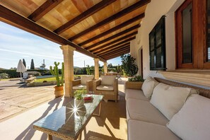 An outdoor patio with a glass table, wicker furniture, and a white sofa. - Stylish Retreat, A/C, Private Pool - Walking Distance (15mins) to Port de Pollenca & Beach! (Pollença)
