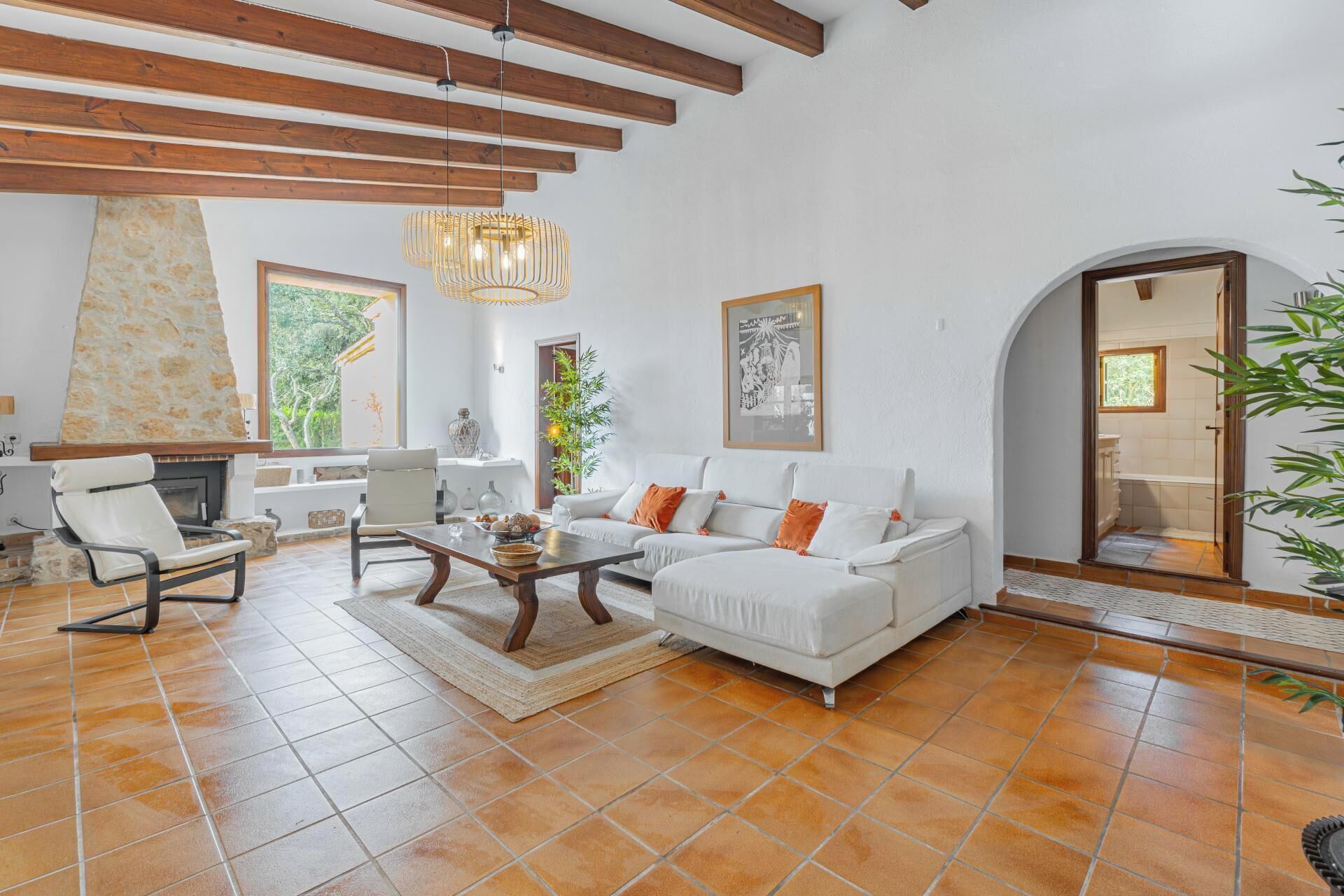 Uma sala de estar espaçosa com lareira de pedra, um sofá branco e uma mesa de jantar.