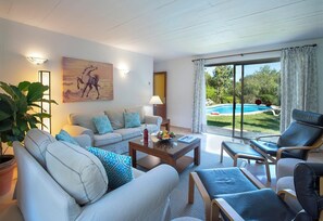 A living room with a sofa, armchairs, a coffee table, and a painting. - Lovingly Maintained Country House, A/C, Private Pool, Landscaped Gardens - 4km from Pollenca! (Pollença)