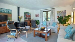A living room with a fireplace, sofa, armchairs, a coffee table, and a television. - Lovingly Maintained Country House, A/C, Private Pool, Landscaped Gardens - 4km from Pollenca! (Pollença)