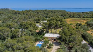 An aerial view of a property with a swimming pool, surrounded by dense forest, and a view of the sea. - Single Storey Villa, A/C, Private Pool - Just a 5min Walk to the Picturesque Cove of Cala Sa Nau! (S´Horta)