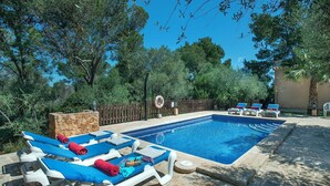 A swimming pool with lounge chairs, a stone wall, and a wooden fence. - Single Storey Villa, A/C, Private Pool - Just a 5min Walk to the Picturesque Cove of Cala Sa Nau! (S´Horta)