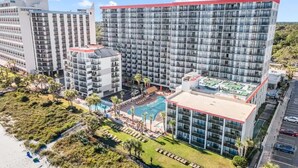 A multi-story hotel with a rooftop pool, a beachside location, and a parking area. - Park at Your Door! Direct Oceanfront + Waterpark (Myrtle Beach)