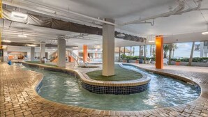 A swimming pool with a tiled edge, surrounded by a brick walkway, and indoor pillars. - Park at Your Door! Direct Oceanfront + Waterpark (Myrtle Beach)