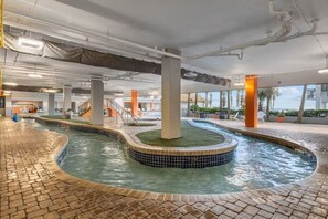 Ein Schwimmbecken mit einer gefliesten Kante, umgeben von einem Pflasterweg und Säulen im Innenbereich.