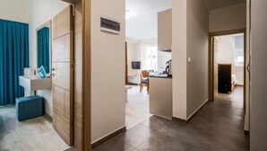 Habitación de hotel con puerta de madera, baño con lavamanos, una silla azul y un escritorio con silla.