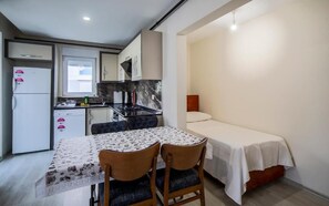 A compact kitchen with a refrigerator, stove, and dining table with chairs. - Sitti Apart Otel (Konyaaltı)