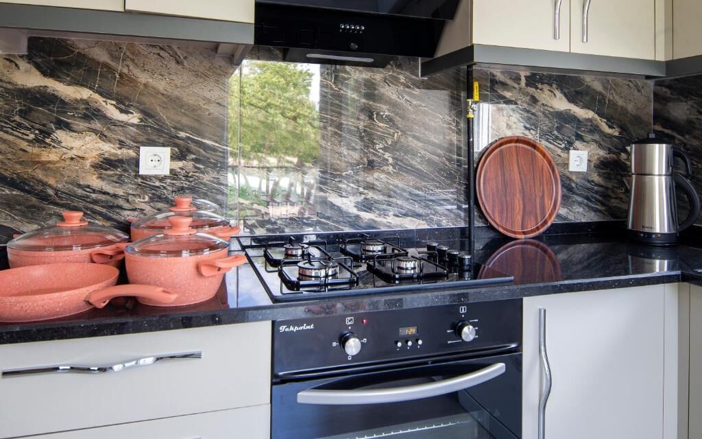 A kitchen with a gas stove, pots, a coffee maker, and a wooden bowl on the counter.