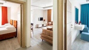 Habitación de hotel con cama, escritorio, sofá, televisión y baño con lavamanos y espejo.
