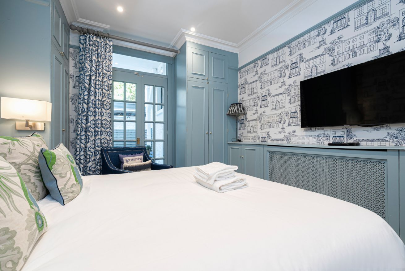 Une chambre d’hôtel avec un grand lit, un téléviseur fixé au mur et une fenêtre avec des rideaux.