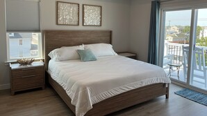 Una camera da letto con un letto grande, una testiera in legno, due comodini, una finestra con persiane e un balcone con vista.