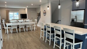 Una cucina moderna con isola centrale, sgabelli da bar bianchi e frigorifero integrato.