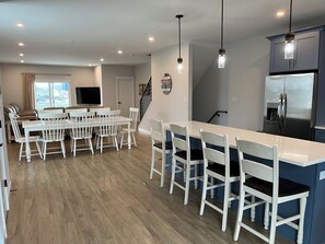 A modern kitchen with a central island, white bar stools, and a built-in refrigerator. - Life is Better at the Beach! (Wildwood)