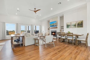 Un salon spacieux doté d’une cheminée, de parquet et d’un ventilateur de plafond.