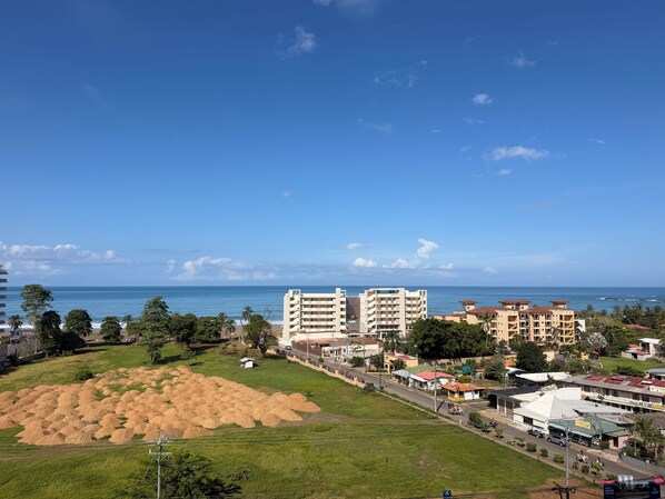 Un paysage urbain côtier avec une vaste plage de sable, des bâtiments et un ciel bleu dégagé.