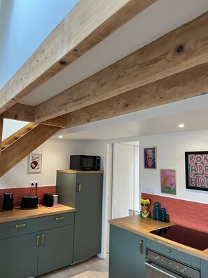 A kitchen with wooden beams, a microwave, cabinets, and a sink. - Le Cocon des Sacres (Reims)