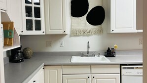 A kitchen with white cabinets, a built-in sink, and a decorative wall hanging. - Spacious 2BR Guest House - Perfect for Remote Work, Family and Pet-Friendly (Las Vegas)