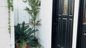 A black door with a textured white wall, a potted plant, and a doormat. - Spacious 2BR Guest House - Perfect for Remote Work, Family and Pet-Friendly (Las Vegas)