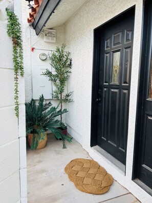A black door with a textured white wall, a potted plant, and a doormat. - Spacious 2BR Guest House - Perfect for Remote Work, Family and Pet-Friendly (Las Vegas)