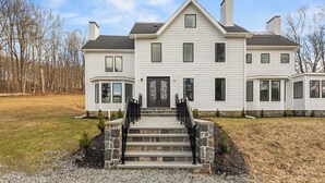 A two-story house with a front entrance, a stone staircase, and a driveway. - Grand 8BR Estate w/ Game Room (Morristown)