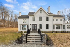 A two-story house with a front entrance, a stone staircase, and a driveway.
