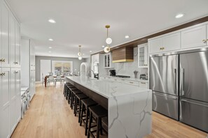Une cuisine moderne dotée d’un îlot central, d’appareils électroménagers en acier inoxydable et d’un grand espace de salle à manger.