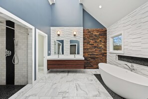 Un baño moderno con una bañera independiente, ducha a ras de suelo y tocador con espejo.