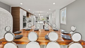 A modern kitchen with white cabinets, a central island, and a dining area with a wooden table and chairs. - Grand 8BR Estate w/ Game Room (Morristown)