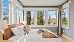 A bedroom with a large bed, multiple windows, and a view of trees. - Grand 8BR Estate w/ Game Room (Morristown)