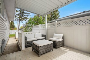 Eine überdachte Terrasse mit Korbmöbeln und einem weißen Zaun.