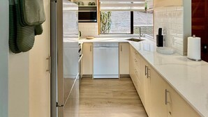 Een moderne keuken met een vaatwasser, magnetron en uitzicht.