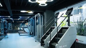 Ett gym med trappmaskiner, styrketräningsmaskiner och en neonskylt med texten ”Neptune”.