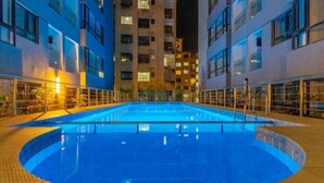 En pool med cirkelformad design, omgiven av en gångväg och glasräcken.