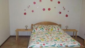 Een slaapkamer met een houten bed, twee nachtkastjes en een bloemenprintbeddeken.