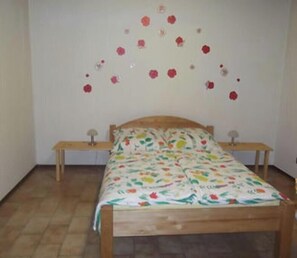 Ein Schlafzimmer mit einem hölzernen Bett, zwei Nachttischen und einer Bettdecke mit Blumenmuster.