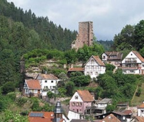 Ein Dorf mit traditionellen Häusern, einem markanten Turm und üppigem Grün.