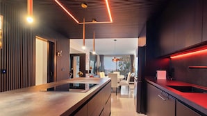 A modern kitchen with a central island, dark cabinetry, and pendant lighting.