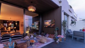 An outdoor seating area with modern furniture, a large window, and a view of the cityscape.