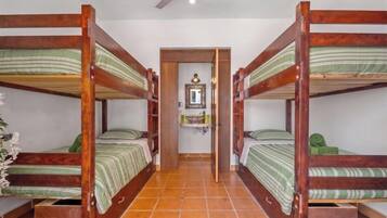 A room with four bunk beds, a small bathroom with a mirror, and a tiled floor.